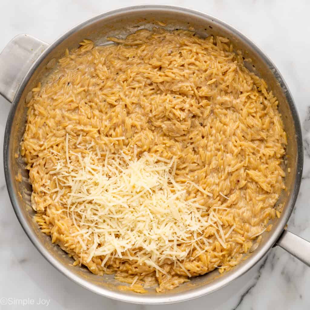 Overhead of skillet of One Pot Lemon Chicken and Orzo with grated parmesan cheese