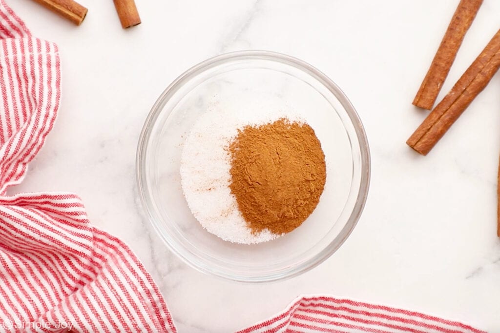 Overhead of bowl of Snickerdoodles ingredients with cinnamon sticks sitting beside