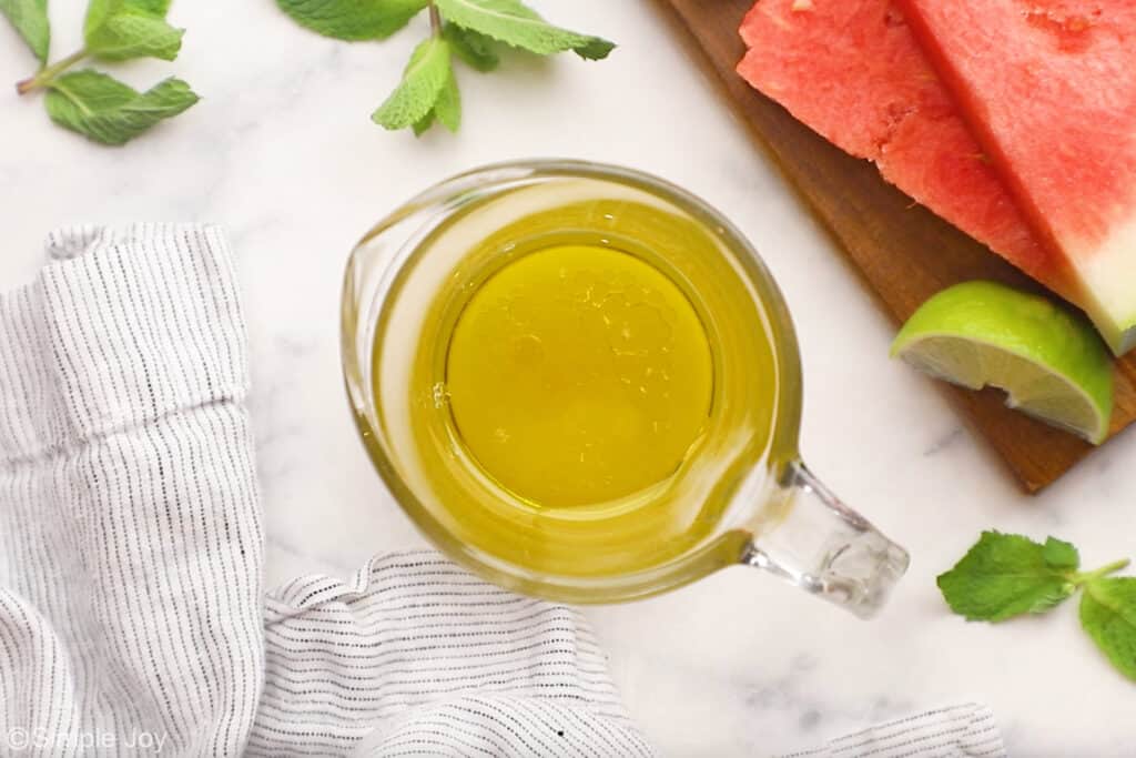 Overhead of glass measuring cup of watermelon salad dressing ingredients