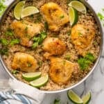 Overhead of skillet of One Pot Coconut Lime Chicken over rice, garnished with fresh cilantro and lime wedges