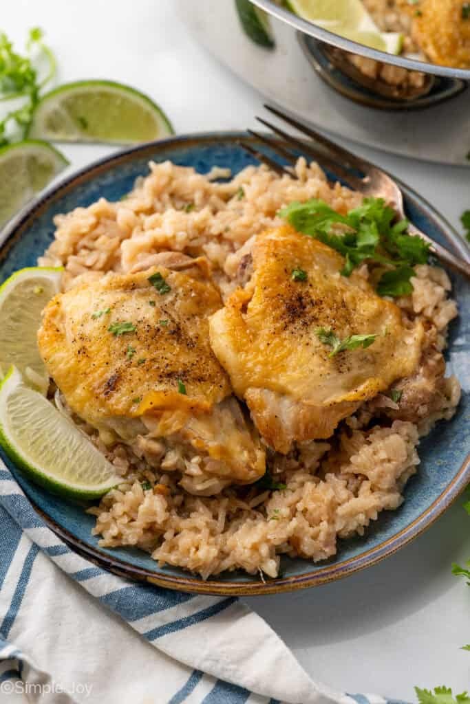 Plate of One Pot Coconut Lime Chicken over rice, garnished with cilantro and lime wedges