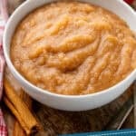 Pinterest graphic for applesauce. Image shows a bowl of applesauce with apples and cinnamon sticks sitting beside. Says "tried & tested applesauce recipe simplejoy.com"