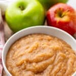 Pinterest graphic for applesauce recipe. Says "the best applesauce recipe simplejoy.com" Image shows a bowl of applesauce with two apples and two cinnamon sticks sitting beside