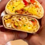 Pinterest graphic for Breakfast Burritos. Image shows person's hands holding two halves of a Breakfast Burrito. Says "the best Breakfast Burritos simplejoy.com"