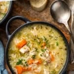 Pinterest graphic for chicken and rice soup. Says "the best chicken & rice soup simplejoy.com" Image shows overhead of bowl of chicken and rice soup garnished with fresh parsley, spoons and slices of bread sitting beside