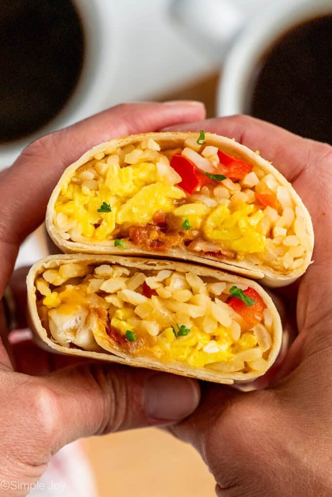 Person's hands holding two Breakfast Burritos