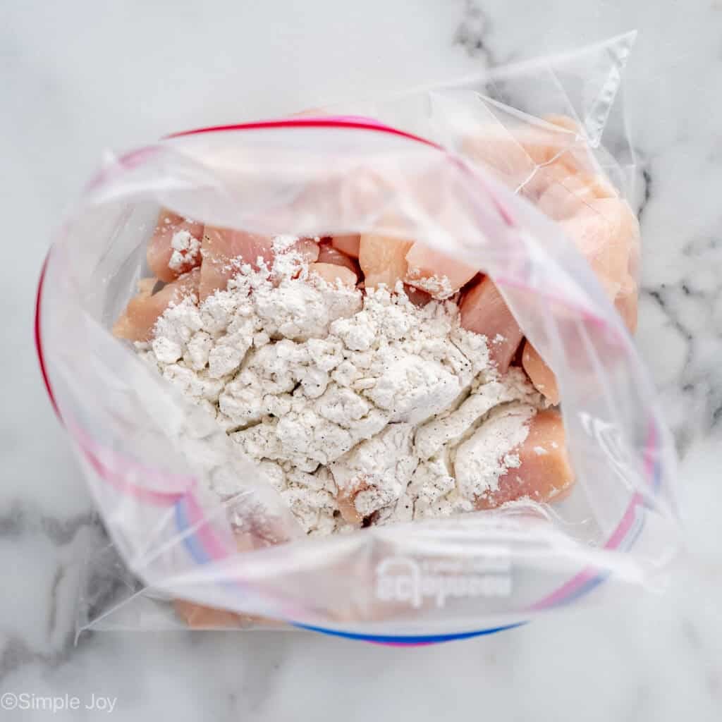 Overhead of plastic bag of chicken and flour mixture to make Baked Orange Chicken recipe