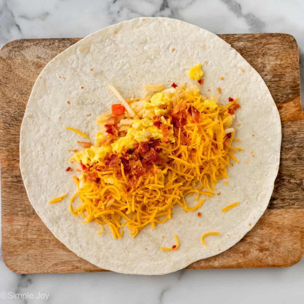 Overhead of tortilla topped with Breakfast Burrito ingredients