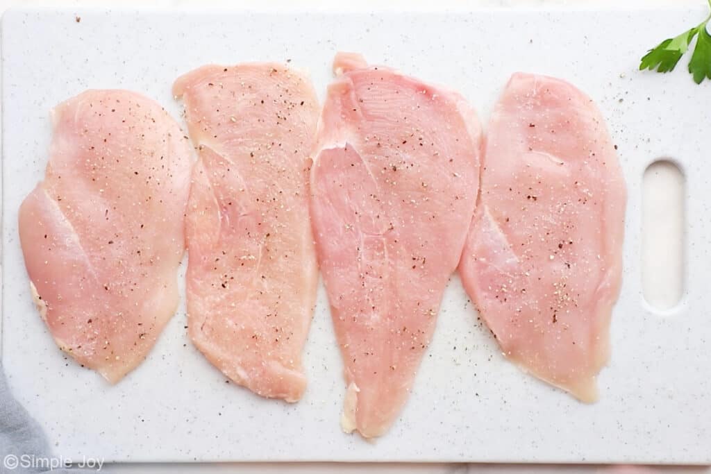 Overhead of chicken cutlets on a cutting board to make parmesan crusted chicken recipe