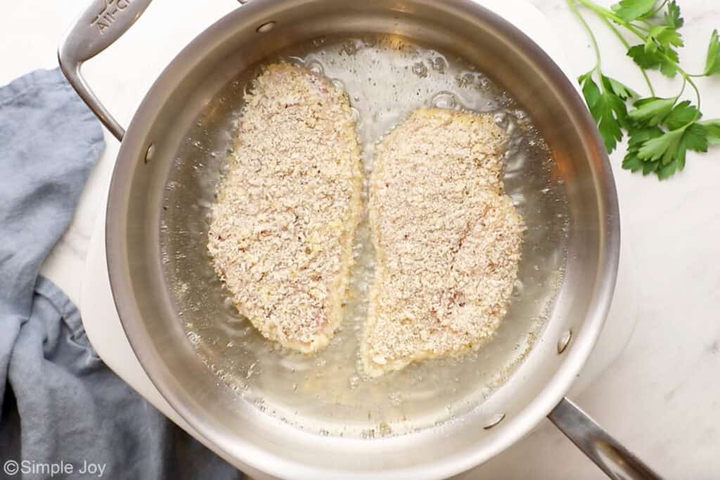 Overhead of parmesan crusted chicken ingredients in a skillet of hot oil