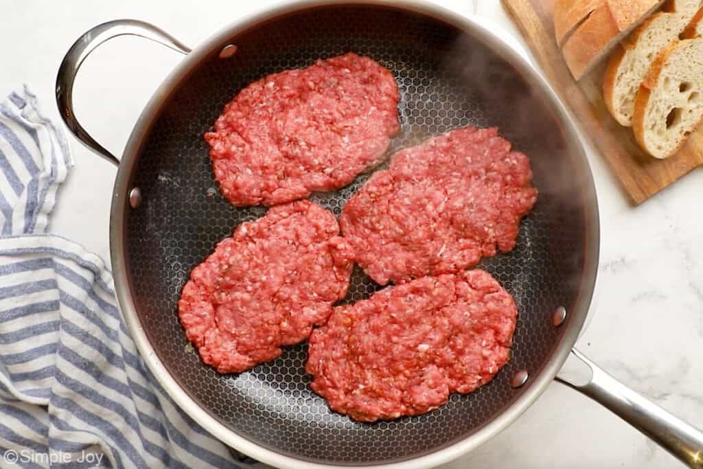 Overhead of four hamburger patty's in a skillet to make patty melts