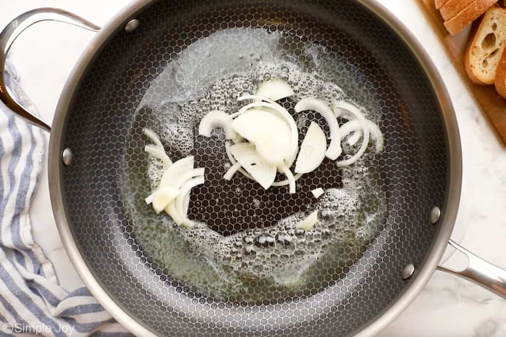 Overhead of skillet of melted butter and sliced onion to make patty melt recipe