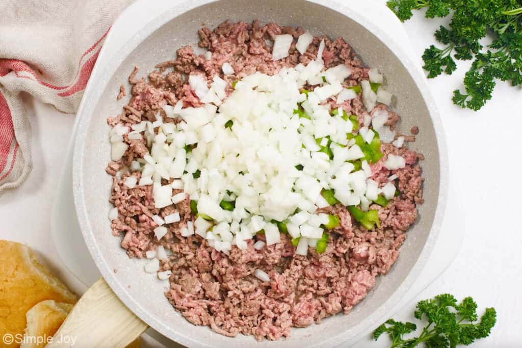 Overhead of skillet of ground beef, diced green peppers, and diced onion to make homemade sloppy joes