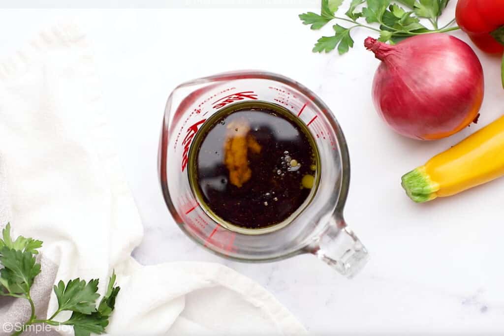 Overhead of glass measuring cup of steak kabob marinade ingredients