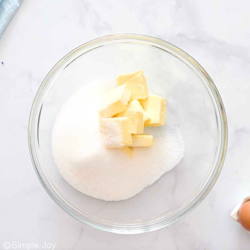 Overhead of glass bowl of butter and sugar to make sugar cookies with sprinkles