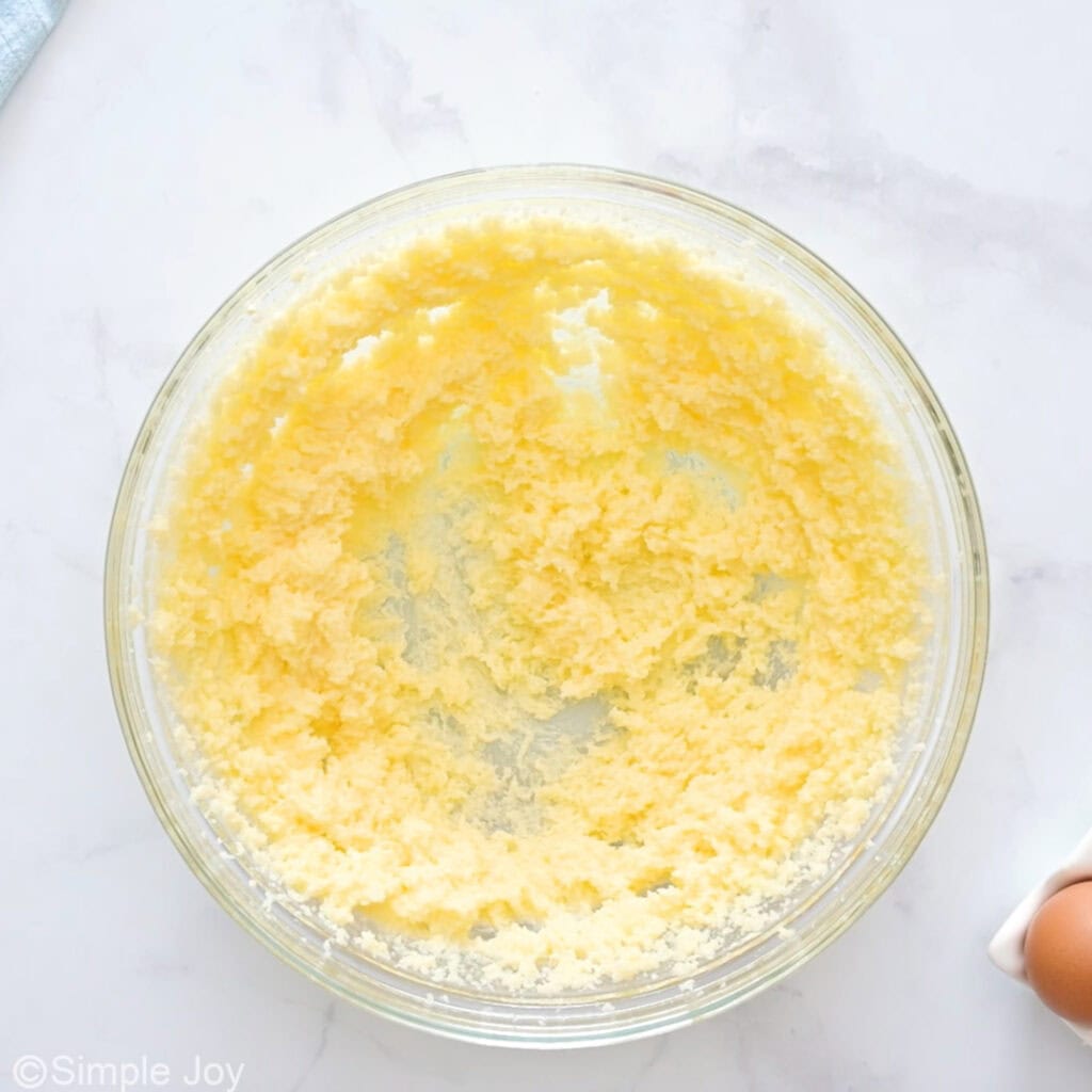 Overhead of glass bowl of butter and sugar to make sugar cookies with sprinkles