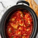 Pinterest graphic for crockpot cabbage rolls. Says "slow cooker cabbage rolls simplejoy.com" Image shows overhead of slow cooker of cabbage rolls