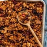 Pinterest graphic for homemade granola recipe. Says "the best homemade granola simplejoy.com" Image shows overhead of sheet pan of granola with wooden spoon