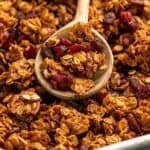 Pinterest graphic for granola recipe. Image shows granola with wooden spoon. Says "the best granola recipe simplejoy.com"