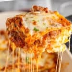 Pinterest graphic for lasagna. Says "the best lasagna recipe simplejoy.com" Image shows a piece of lasagna being lifted out of pan