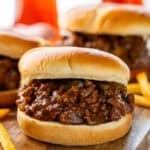 BBQ Sloppy Joes on a wooden board with french fries sitting beside