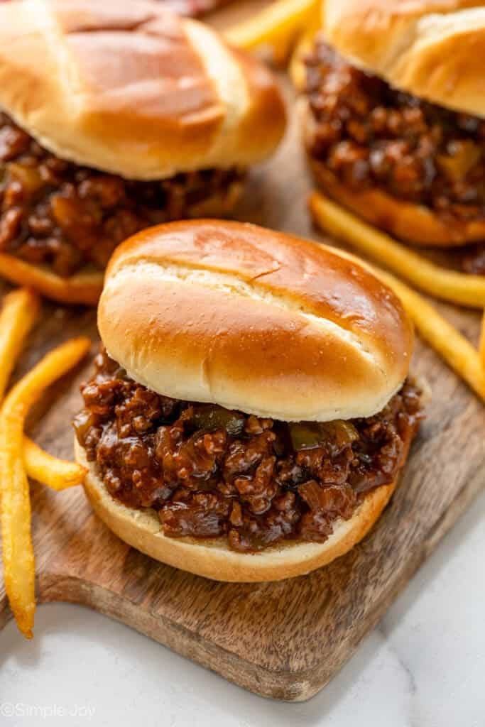 BBQ Sloppy Joes on a wooden board with french fries sitting beside