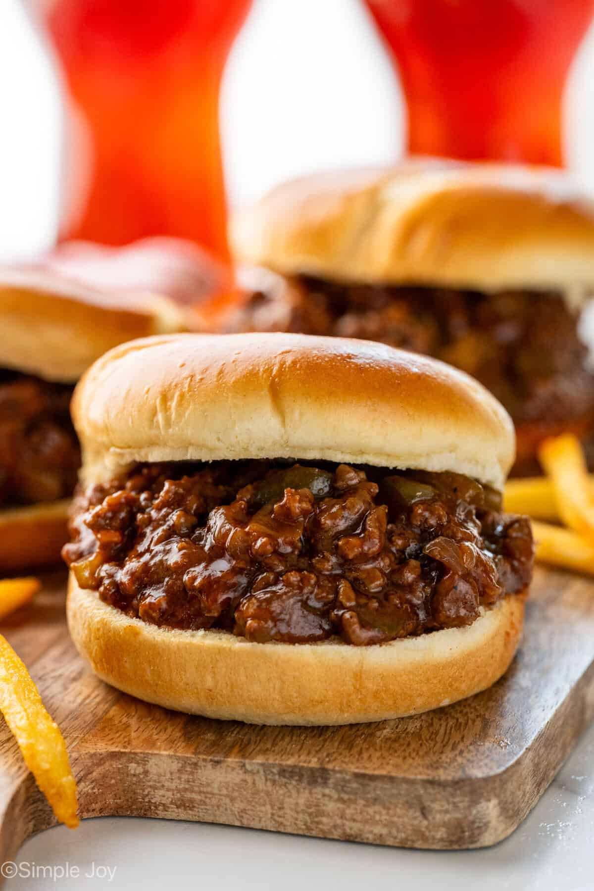 BBQ Sloppy Joes on a wooden board with french fries sitting beside