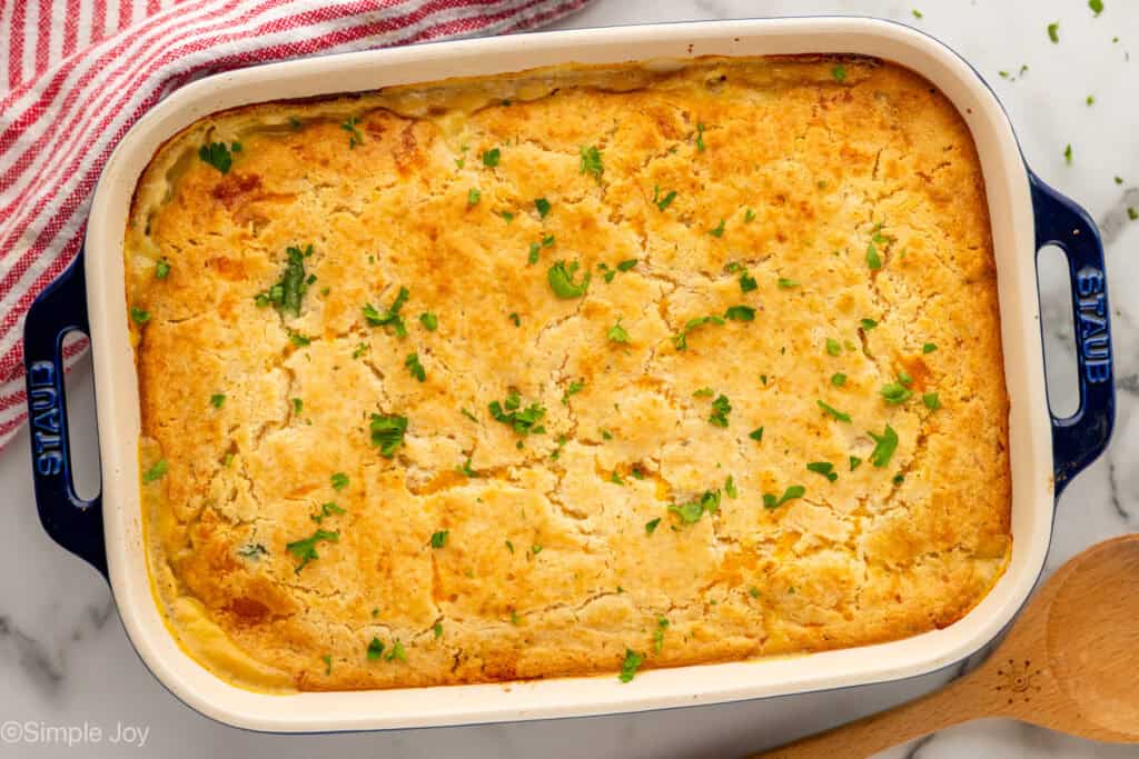 Overhead of baking dish of chicken cobbler with wooden spoon sitting beside