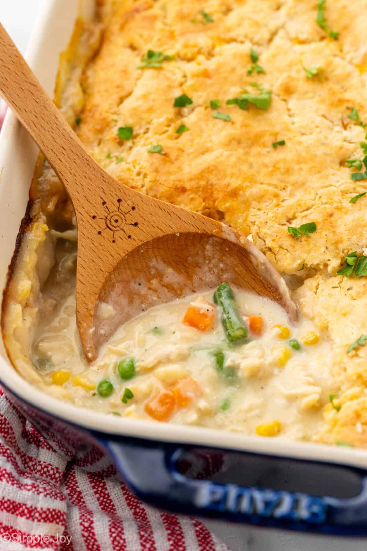 Wooden spoon in casserole dish of chicken cobber