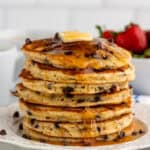 Stack of homemade chocolate chip pancakes topped with butter and syrup.