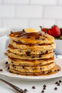 Stack of homemade chocolate chip pancakes topped with butter and syrup.