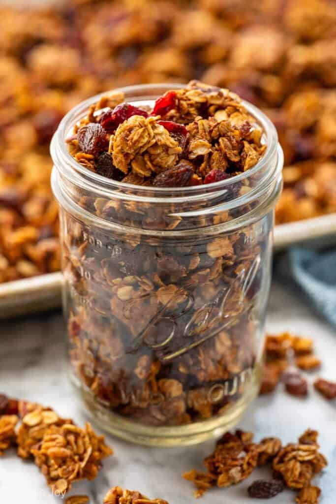 Small mason jar of granola with clusters of granola sitting beside
