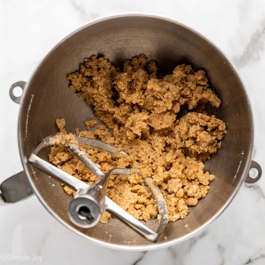 Overhead of apple cookie ingredients in a mixing bowl with paddle attachment