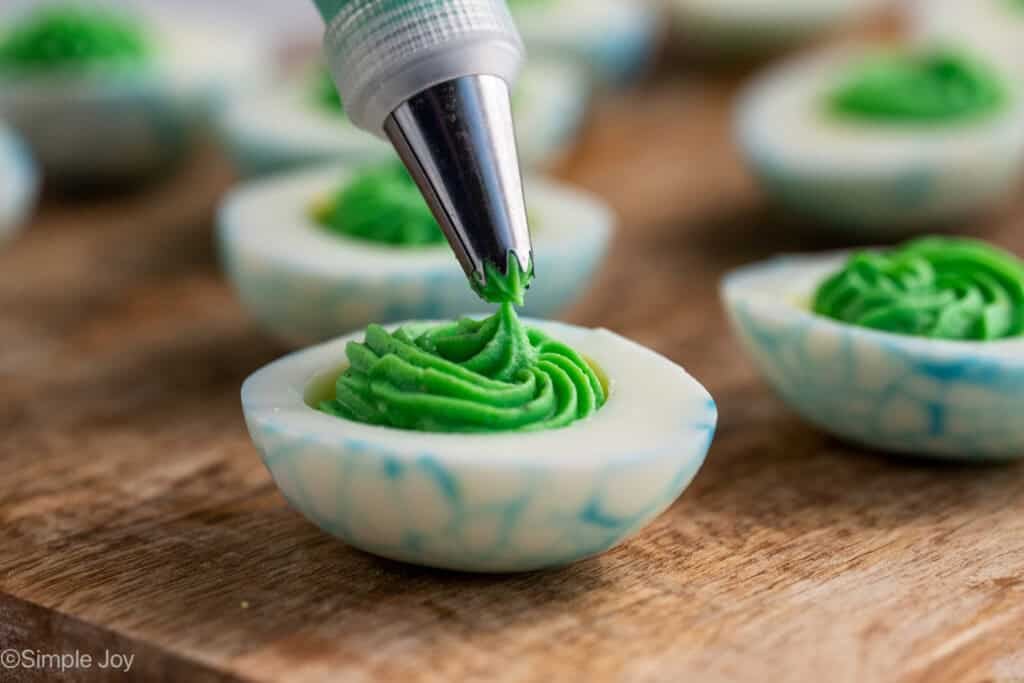 piping set putting Halloween Deviled Egg filling into a hard boiled egg white