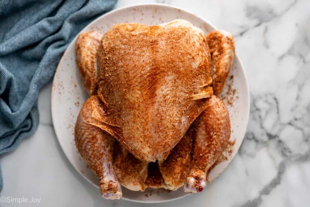Overhead of whole chicken with seasonings on a plate to make Instant Pot Whole Chicken