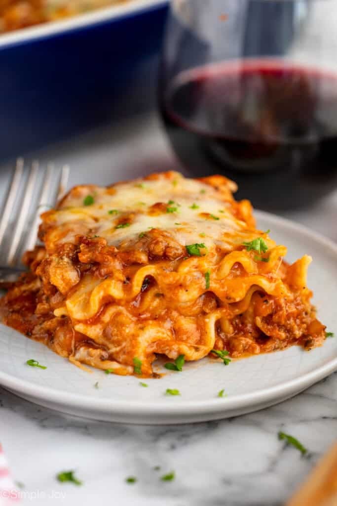 Piece of homemade lasagna on a plate with fork sitting beside