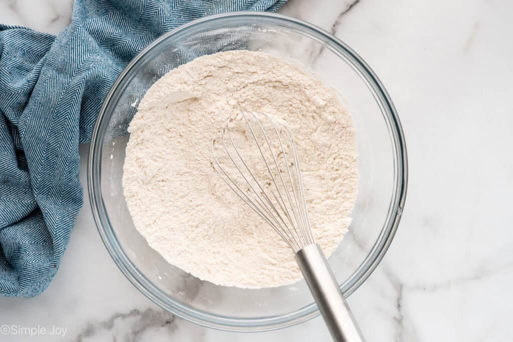 Overhead of glass bowl of banana bread ingredients with whisk