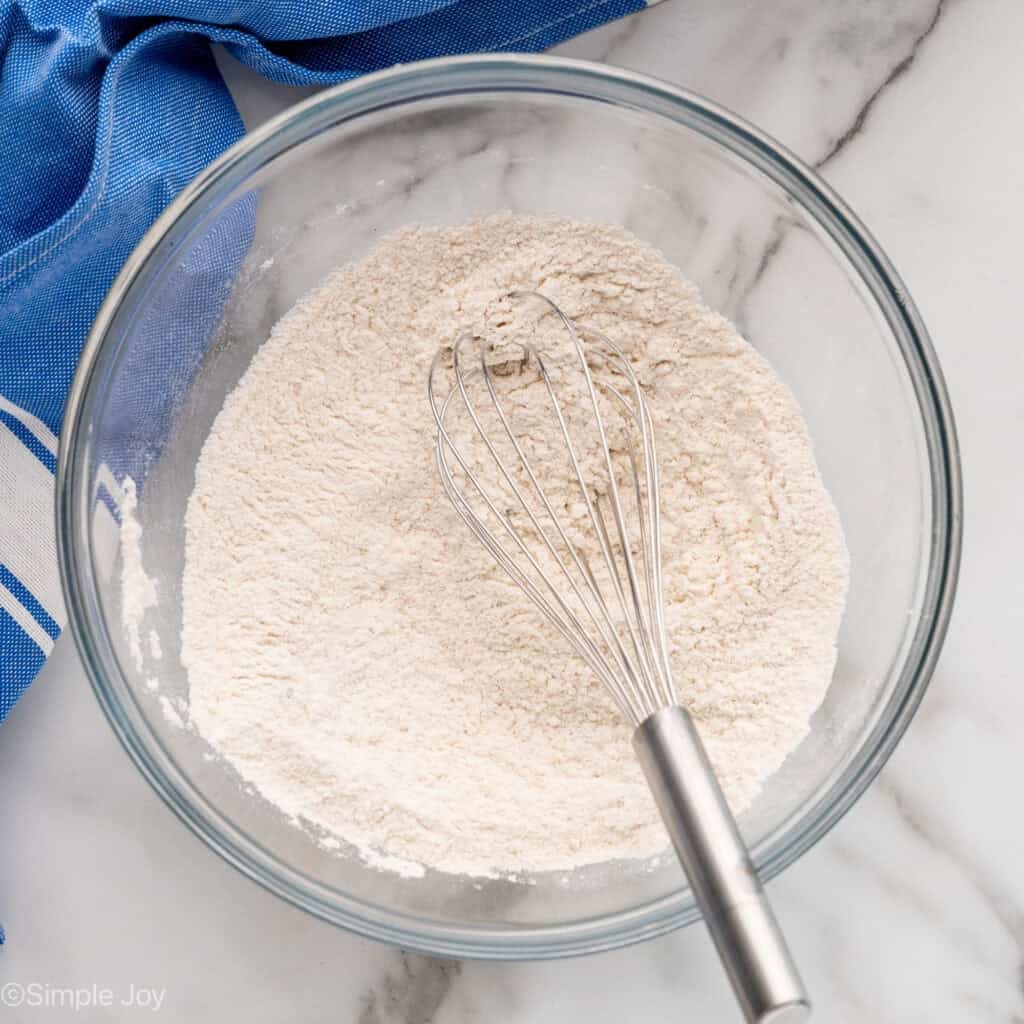 Overhead of bowl of chocolate chip pancakes ingredients and wire whisk