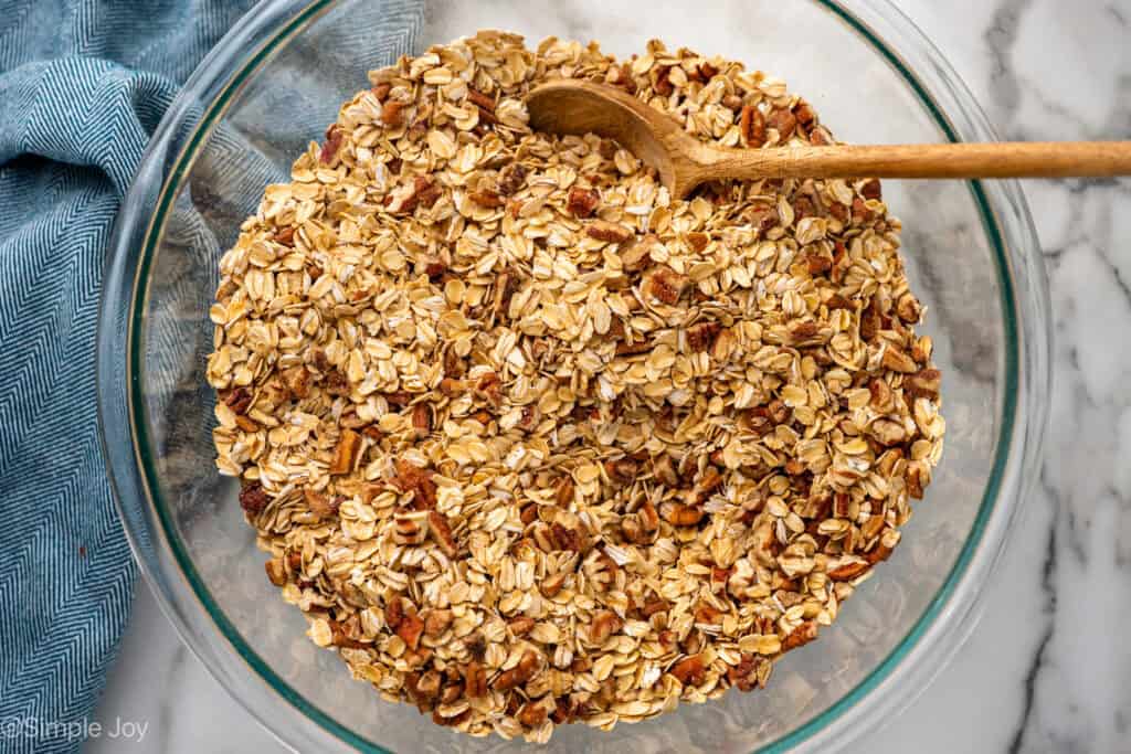 Overhead of bowl of granola ingredients with wooden spoon