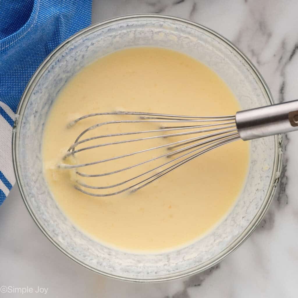 Overhead of bowl of chocolate chip pancakes ingredients and wire whisk