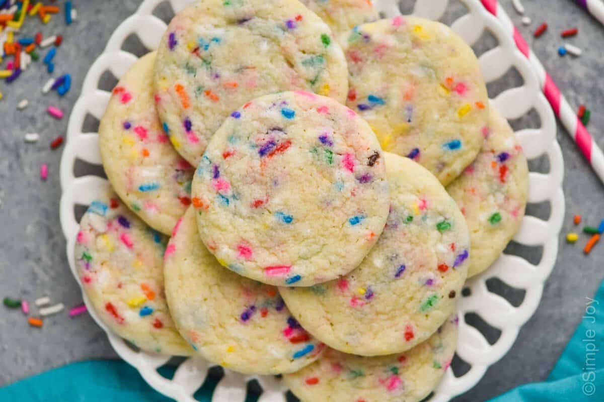 overhead view of a white plate with funfetti cookies, a teal napkin near them, and sprinkles all around the plate