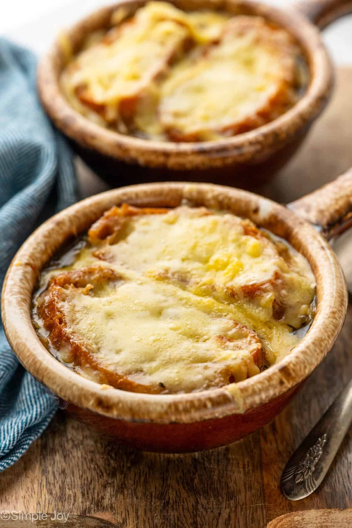 two bowls of french onion soup topped with toasted baguette and melted cheese