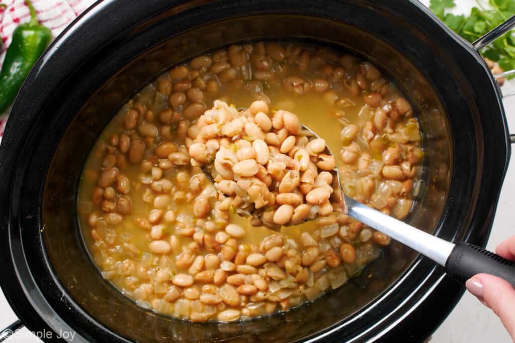 Overhead of slow cooker of pinto beans with spoon scooping beans