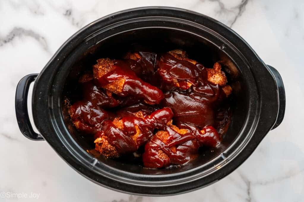 chicken drumsticks coated in BBQ sauce in crock pot