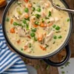 Pinterest graphic for chicken pot pie soup. Image shows overhead of bowl of chicken pot pie soup with spoon. Biscuits and another bowl of soup sitting beside. Says "amazing chicken pot pie soup"
