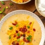 Pinterest graphic for crockpot potato soup. Says "slow cooker potato soup simplejoy.com" Image shows overhead of bowl of crockpot potato soup garnished with shredded cheese, diced bacon and chives.