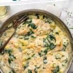 Pinterest graphic for spinach artichoke chicken. Says "the best spinach artichoke chicken simplejoy.com" Image shows overhead of skillet of spinach artichoke chicken with two forks
