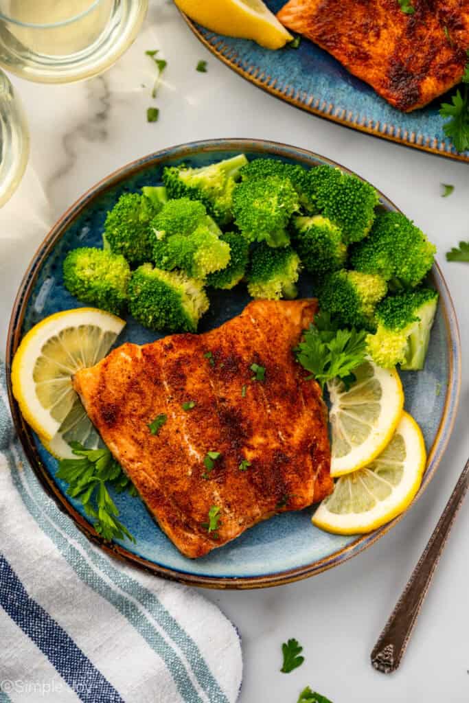 overhead of a plate with broccoli, a filet of cooked salmon and some lemon slices