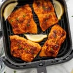 Overhead of air fryer basket of air fryer salmon and lemon slices