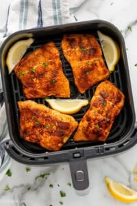 Overhead of air fryer basket of air fryer salmon and lemon slices